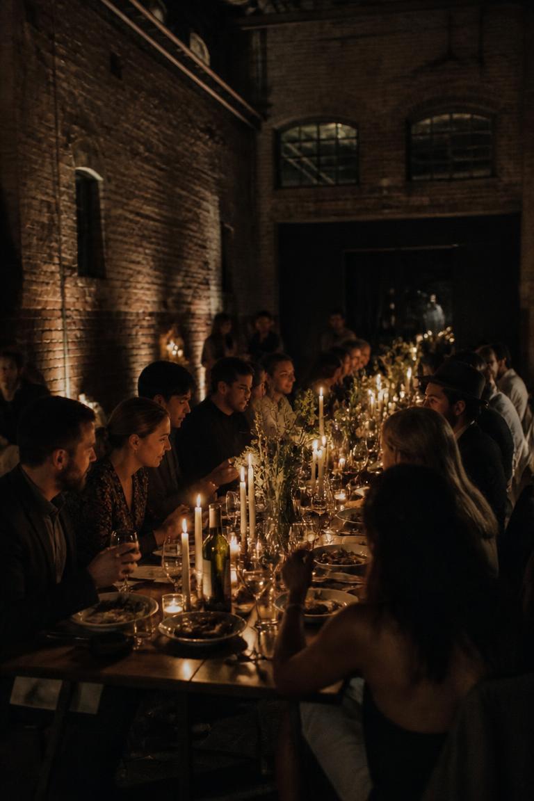 Moody candlelight dinner party in a brick warehouse